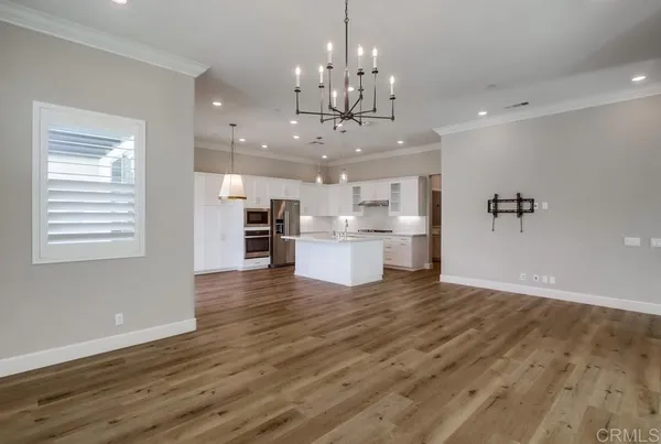 a view of a hallway with wooden floor and a kitchen