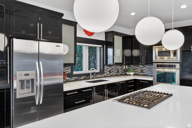 145 Carnesecca Court Mapleton, UT 84664 - Photo 27 of 109 Kitchen featuring dark cabinetry, stainless steel appliances, glass insert cabinets, recessed lighting, and light stone countertops