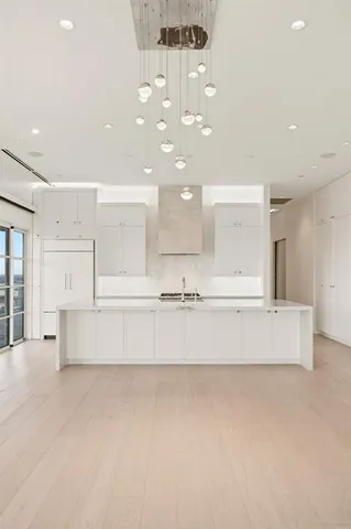 a large white kitchen with a large island oven a stove with white cabinets and couches