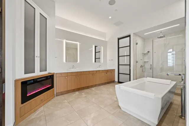 a spacious en suite bathroom with a tub double sink and mirror