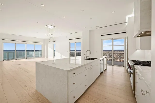 a large white kitchen with cabinets a sink and appliances