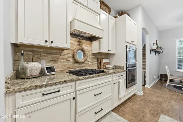 a kitchen with granite countertop white cabinets and a stove with a sink