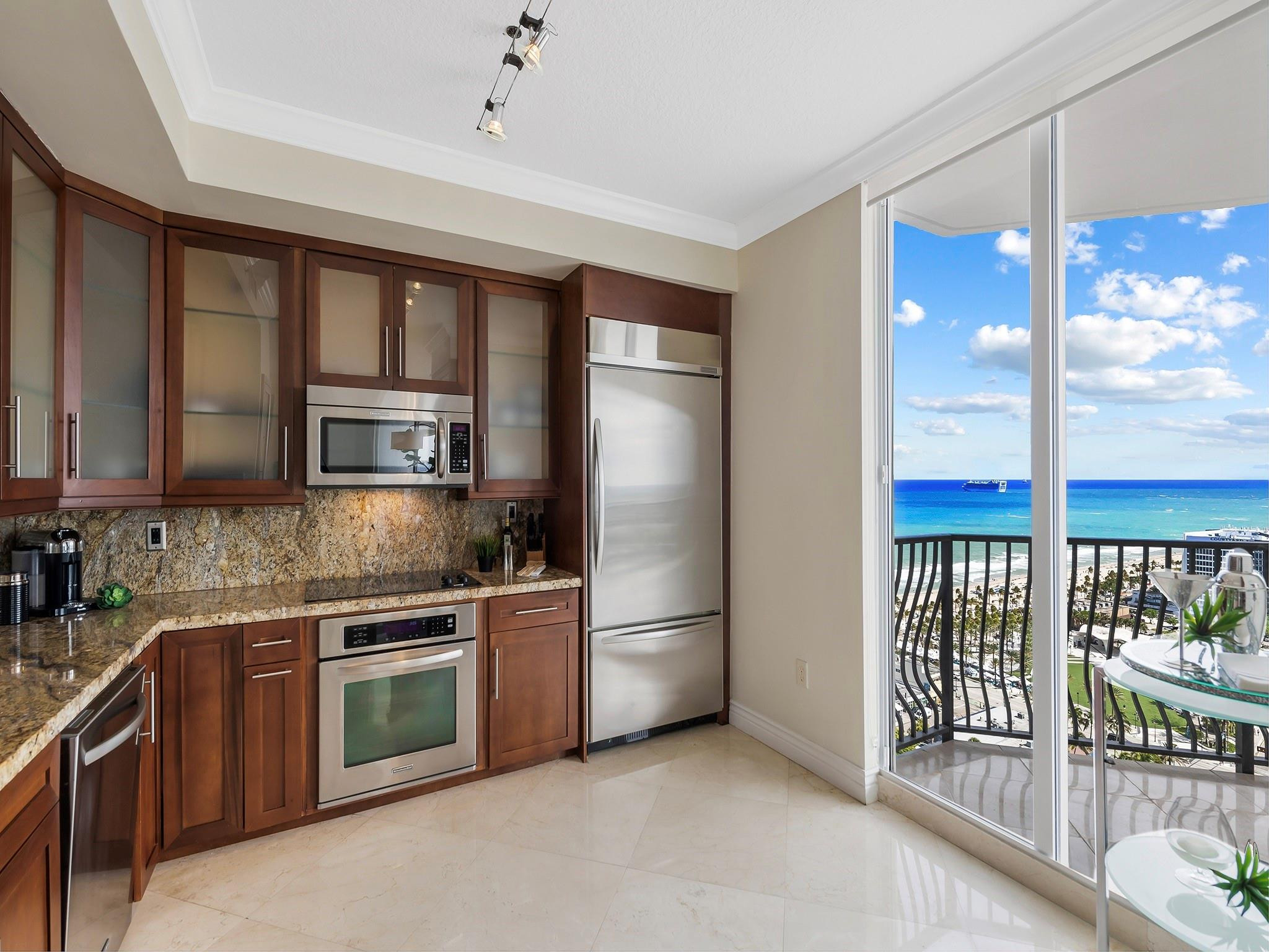 100 South Birch Road, Unit 2504 Fort Lauderdale, FL 33316 - Photo 9 of 42 a kitchen with stainless steel appliances granite countertop a refrigerator a stove and a sink with wooden floor