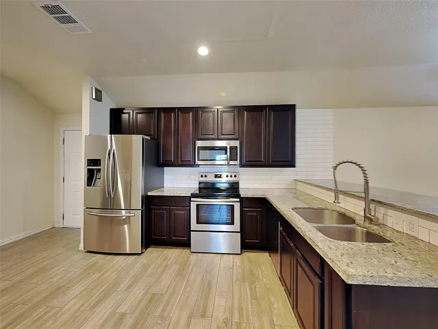 a kitchen with stainless steel appliances granite countertop a refrigerator stove a sink and a granite counter tops