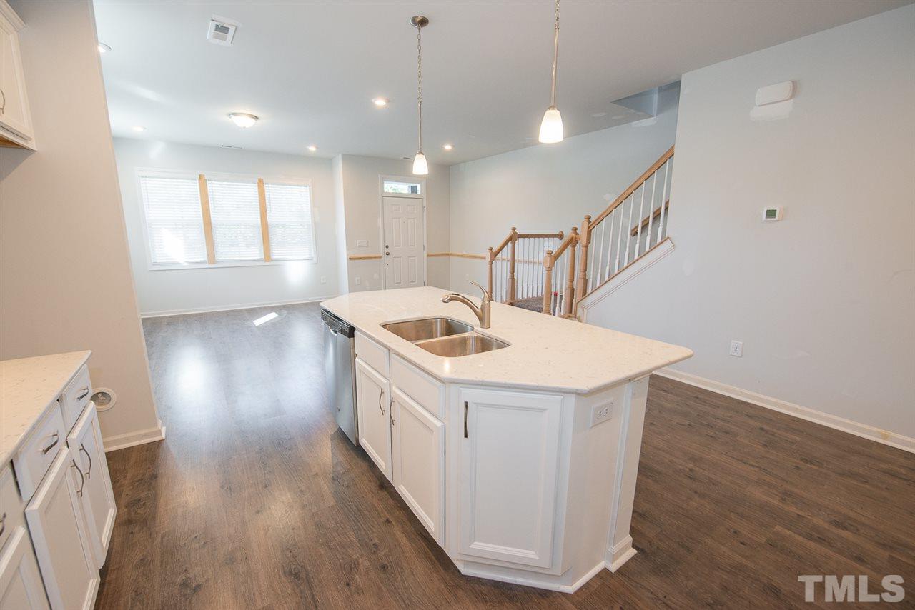3620 Buffaloe Road, Unit 1 Raleigh, NC 27604 - Photo 7 of 25 a kitchen that has a sink a microwave oven a stove and white cabinets with wooden floor