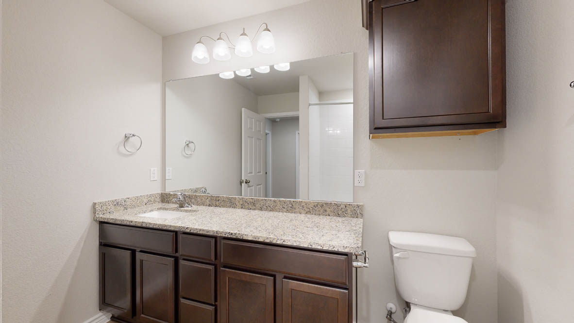405 Creekfall Road Burnet, TX 78611 - Photo 24 of 27 a bathroom with a granite countertop sink a toilet and mirror