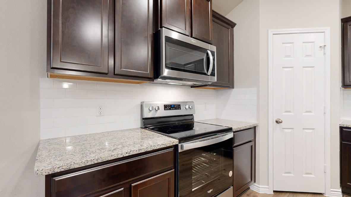 405 Creekfall Road Burnet, TX 78611 - Photo 4 of 27 a kitchen with stainless steel appliances granite countertop a stove microwave and sink