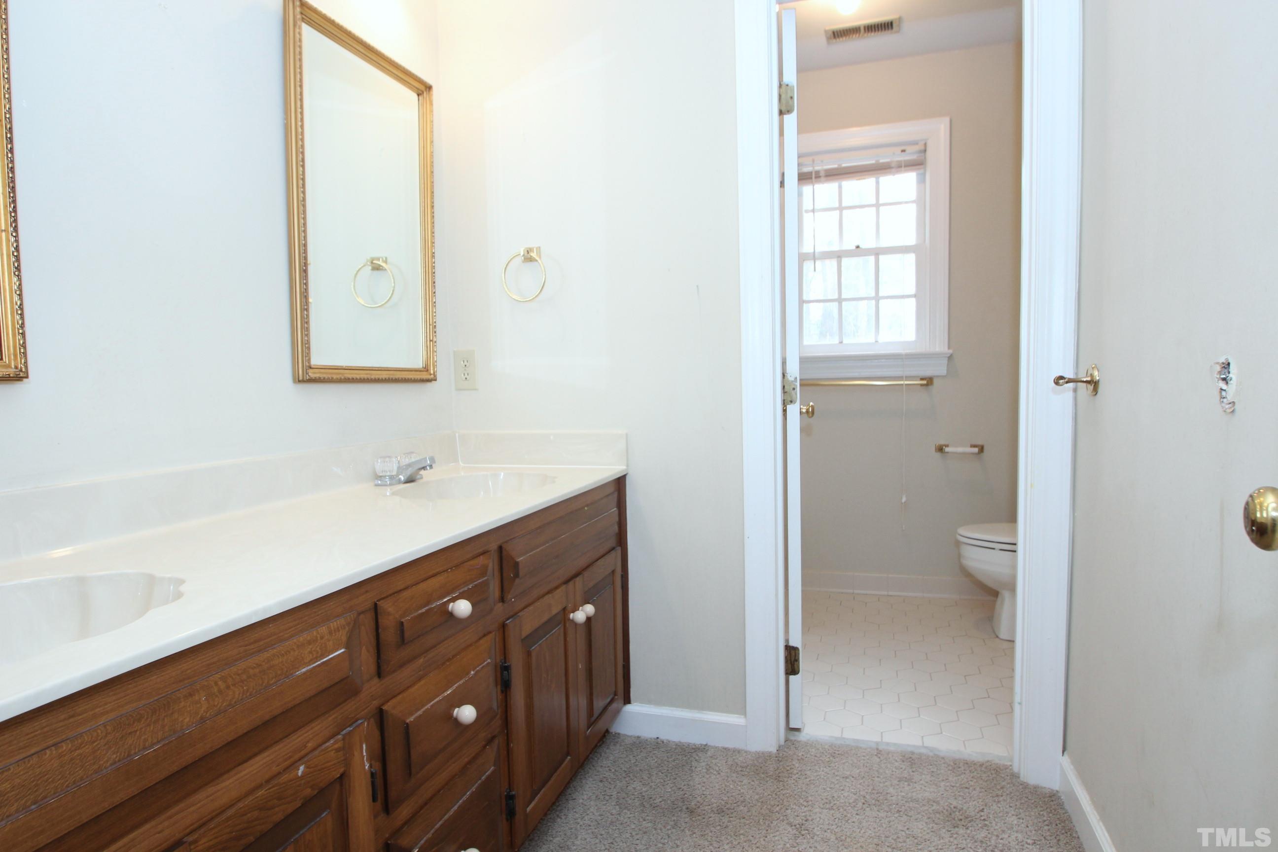 4013 Country Village Drive Raleigh, NC 27606 - Photo 16 of 23 a bathroom with a toilet a sink a mirror and a window