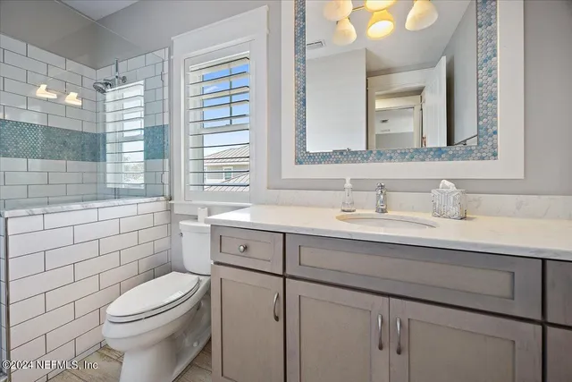 a bathroom with a granite countertop toilet sink and mirror