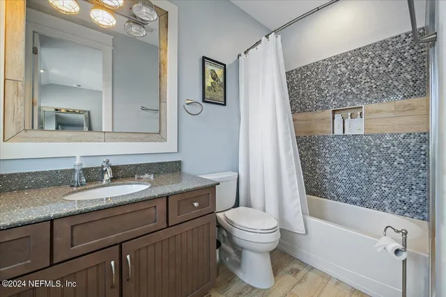 a bathroom with a granite countertop toilet a sink a mirror and shower curtain