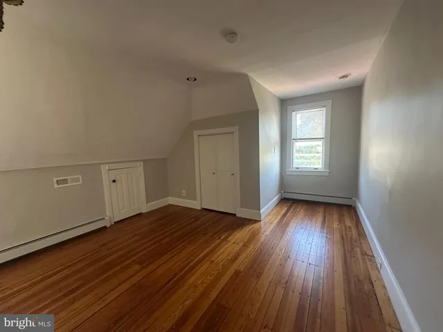 a view of an empty room with wooden floor and window