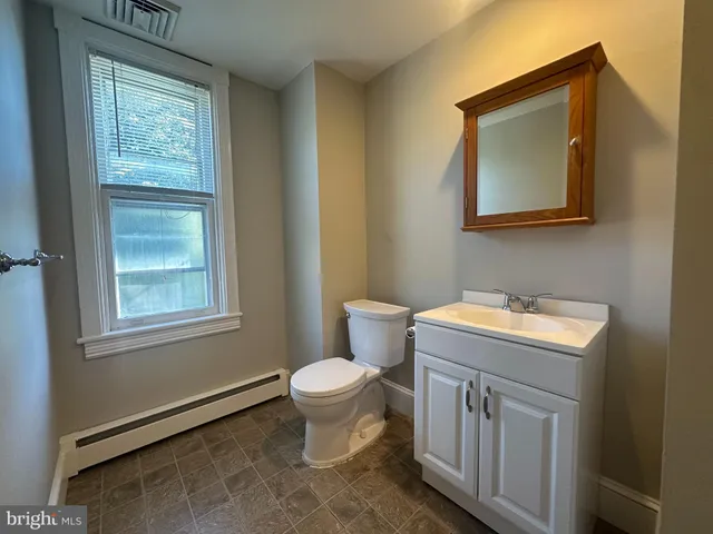 a bathroom with a toilet a sink a mirror and a window