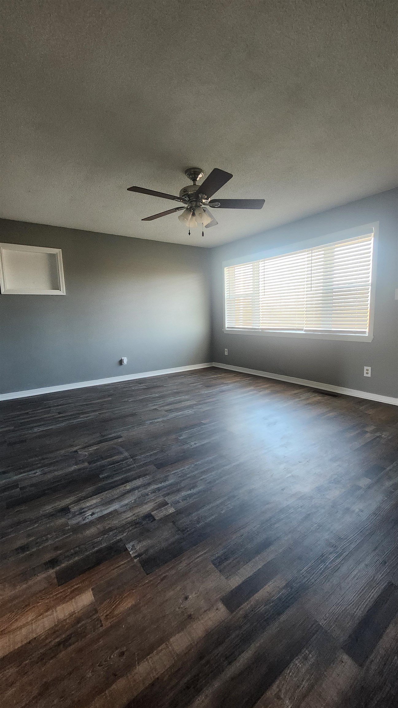 56 Riddick Street Gates, TN 38037 - Photo 5 of 10 an empty room with wooden floor and windows with curtains