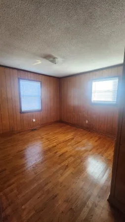 an empty room with wooden floor and windows in it