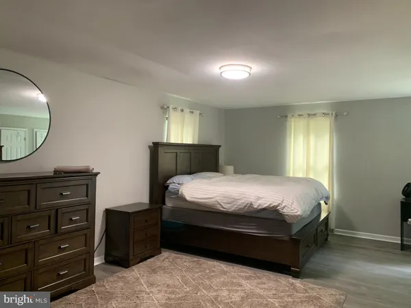 a bedroom with a bed a mirror on dresser and a window