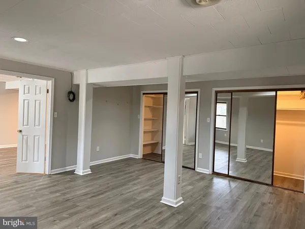 an empty room with wooden floor & windows