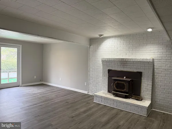 an empty room with wooden floor fireplace and window