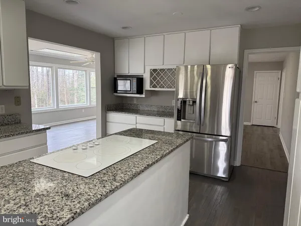 a kitchen with granite countertop a refrigerator a sink a stove a microwave and island