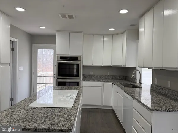 a kitchen with granite countertop a stove and cabinets