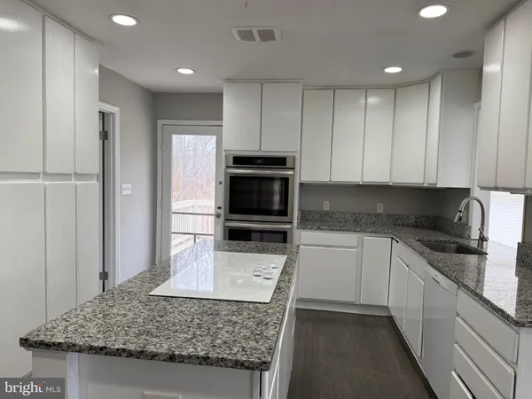a kitchen with kitchen island granite countertop a stove and a sink