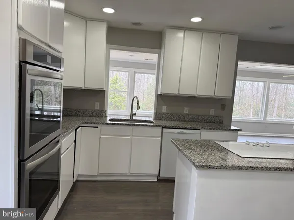 a kitchen with granite countertop stainless steel appliances a stove sink and microwave