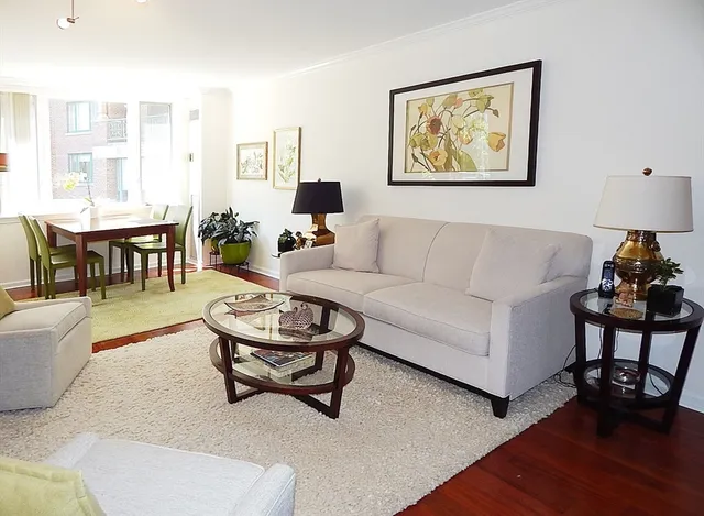 a living room with furniture a wooden floor and a lamp