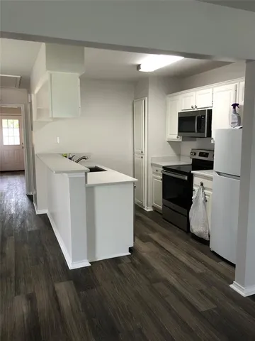 a kitchen with stainless steel appliances a stove top oven a sink with wooden floors and cabinets