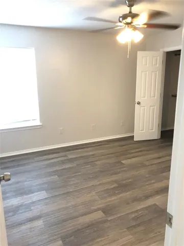 an empty room with wooden floor closet and fan