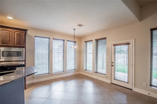 a view of an empty room with kitchen and window