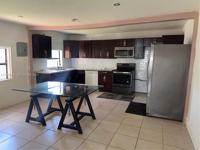 a kitchen with stainless steel appliances kitchen island granite countertop a refrigerator and a stove top oven