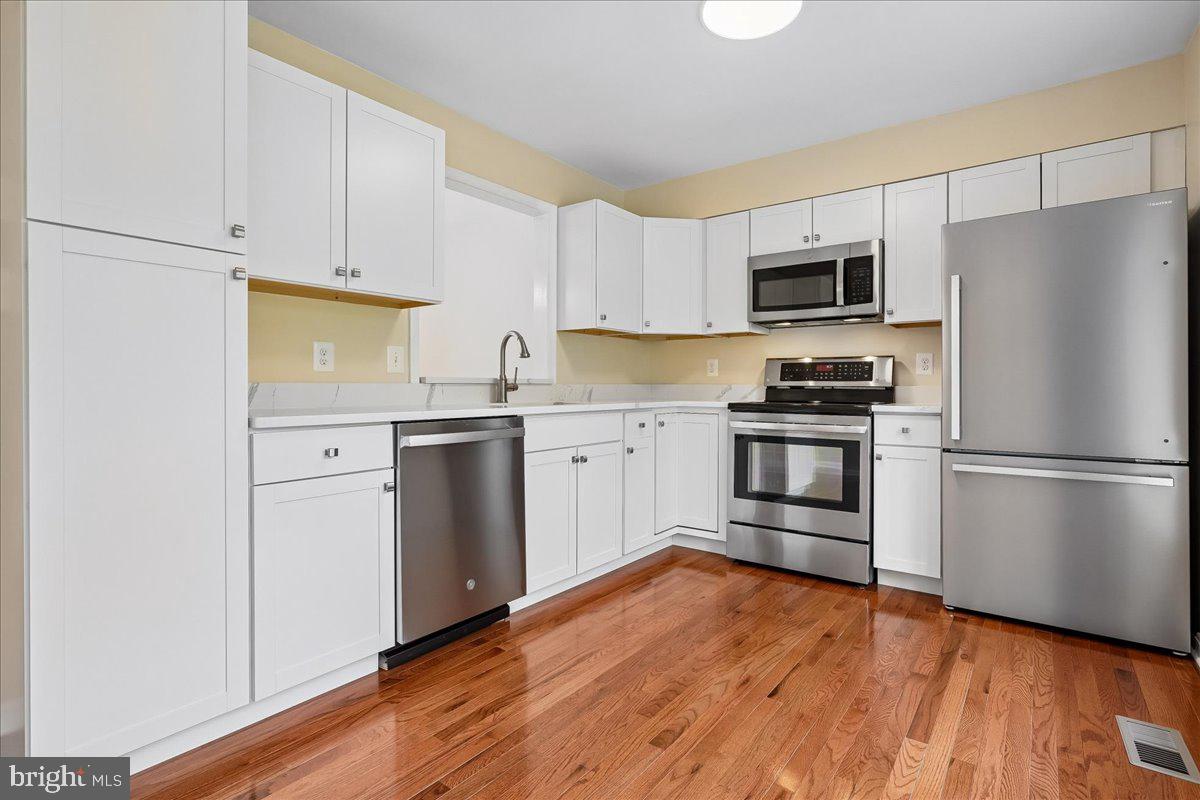 9752 High Water Court Burke, VA 22015 - Photo 6 of 25 a kitchen with cabinets stainless steel appliances and wooden floor