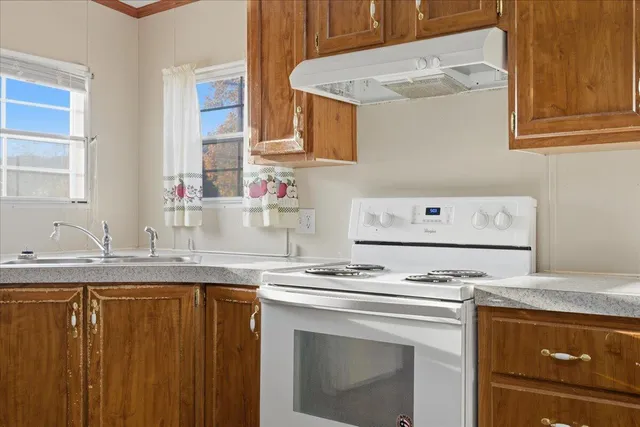 a kitchen with granite countertop cabinets stove top oven and sink