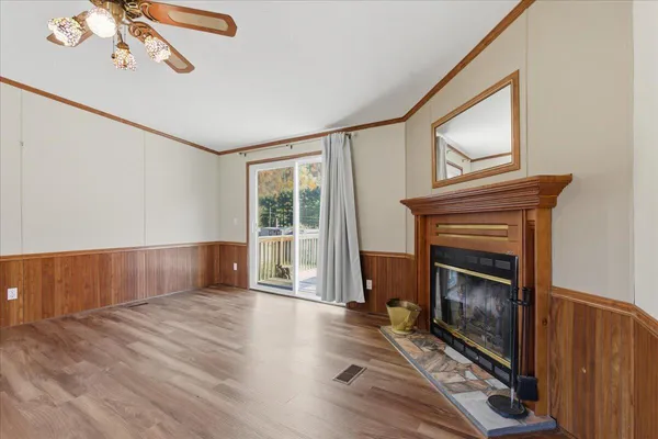 a view of an empty room with wooden floor fireplace and a window