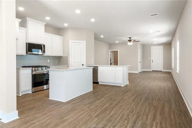 a view of kitchen with microwave a stove top oven and white cabinets