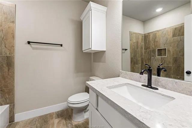 a bathroom with a granite countertop sink toilet and a mirror