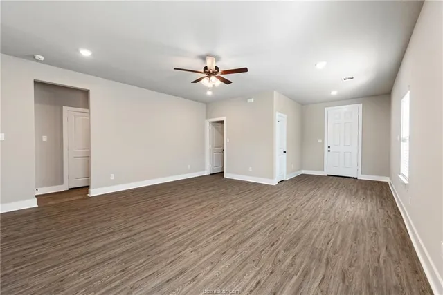 an empty room with wooden floor and a ceiling fan