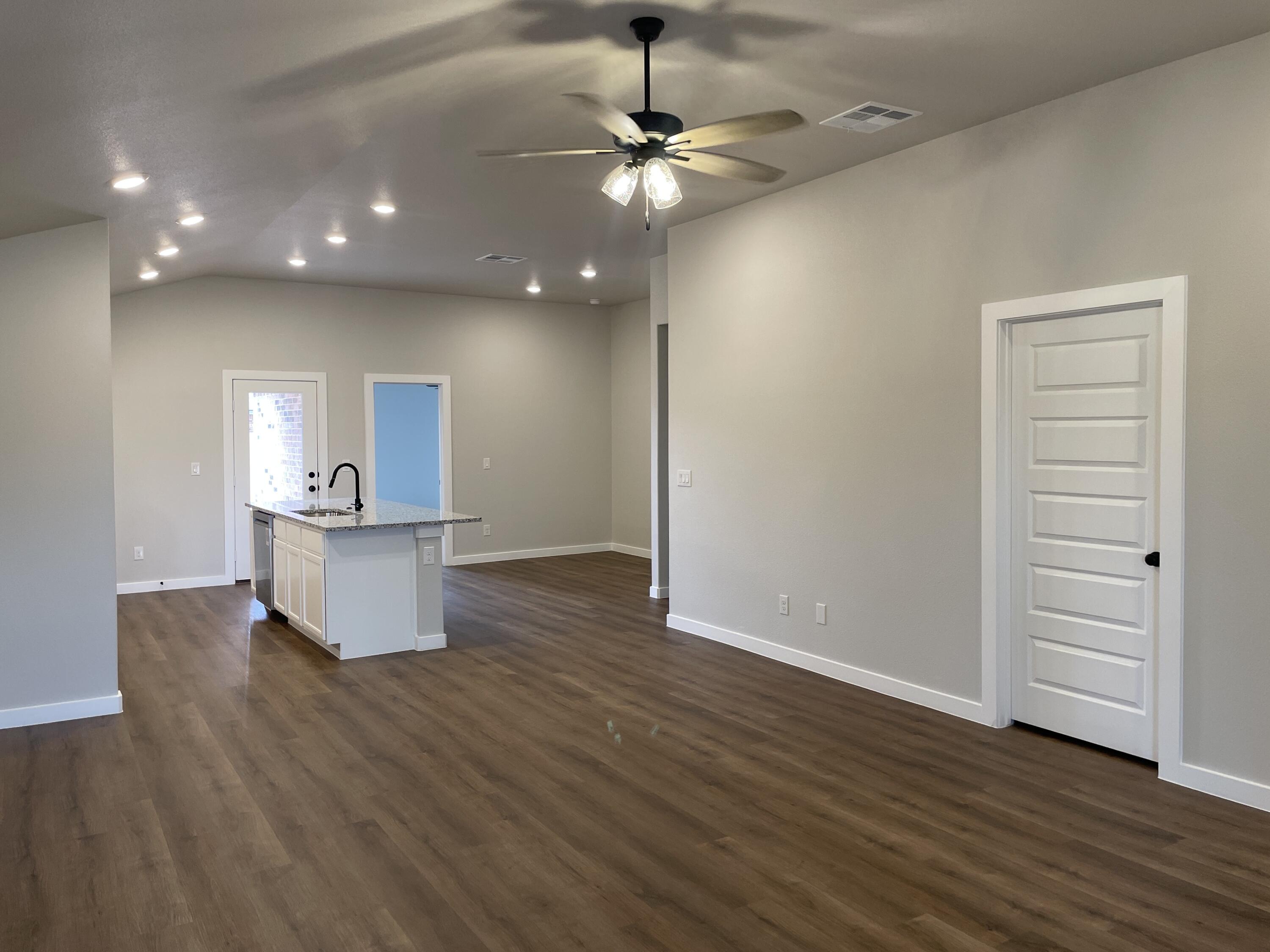 7450 29th Street Lubbock, TX 79407 - Photo 5 of 32 a view of an empty room with wooden floor and a ceiling fan