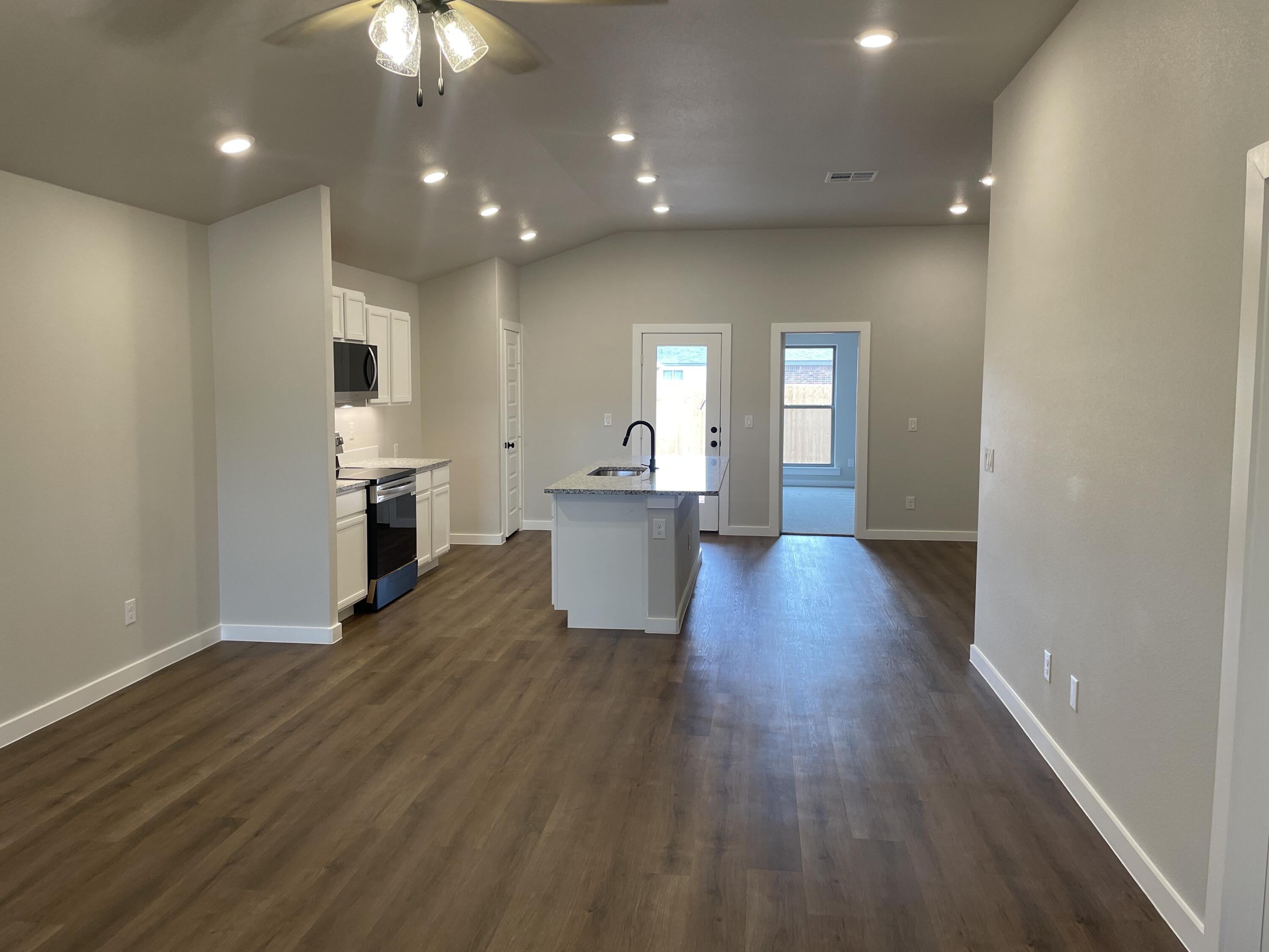 7450 29th Street Lubbock, TX 79407 - Photo 9 of 32 a view of a big room with wooden floor and a kitchen