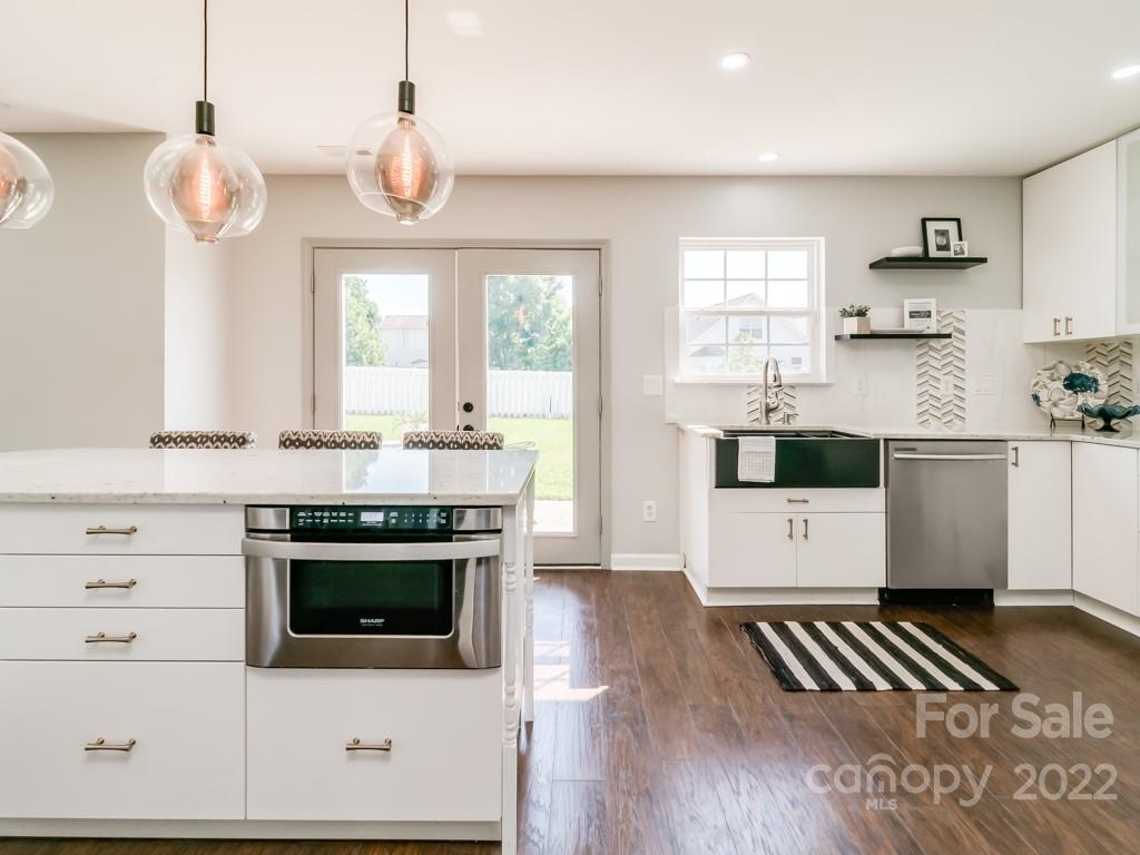 5510 Rogers Road Indian Trail, NC 28079 - Photo 13 of 35 a kitchen with stainless steel appliances a stove a sink and white cabinets with wooden floor