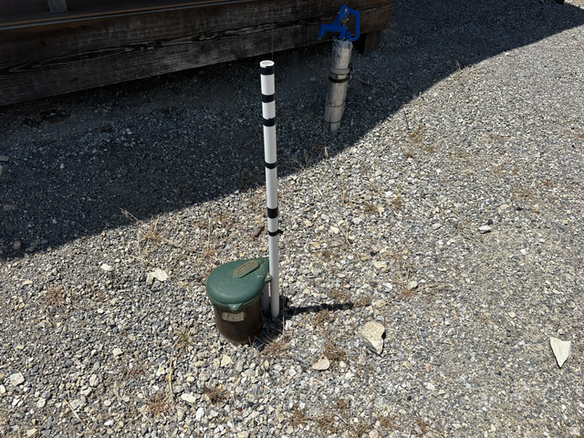 2006 Swenson Valley Road Bancroft, ID 83217 - Photo 42 of 51 Gravel ground cover with a built-in water spigot featuring a blue handle, a white and black striped marker pole, and a green utility box