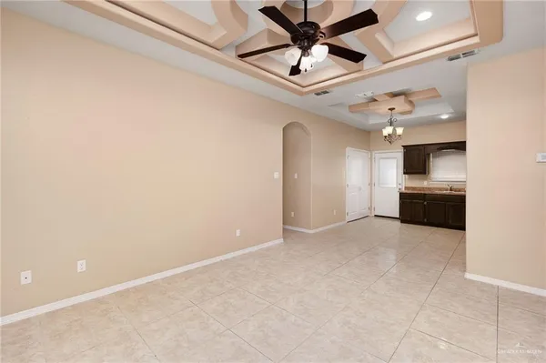 an empty room with a kitchen and a ceiling fan