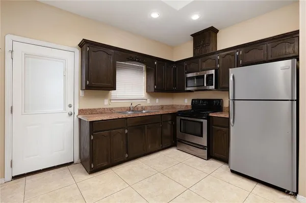a kitchen with granite countertop a refrigerator and a stove top oven