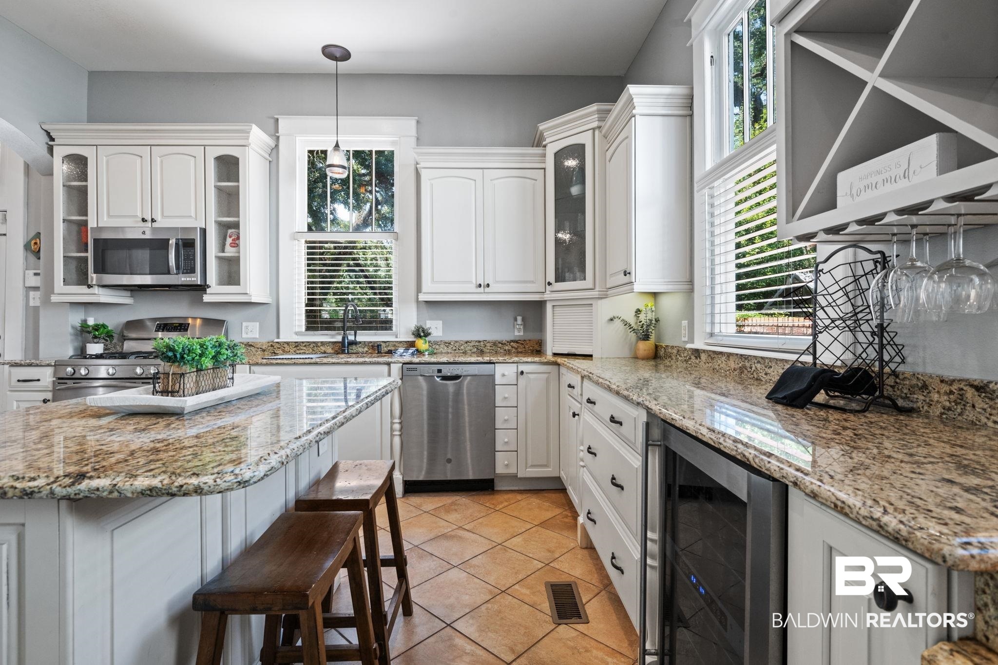 10 South Monterey Street Mobile, AL 36604 - Photo 14 of 45 Kitchen with wine cooler, glass insert cabinets, appliances with stainless steel finishes, white cabinets, and light stone countertops