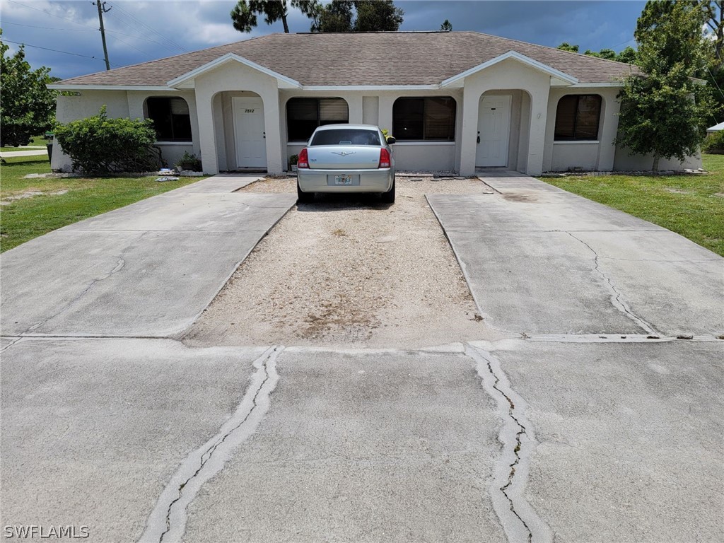 a view of a white house with a yard and large parking space