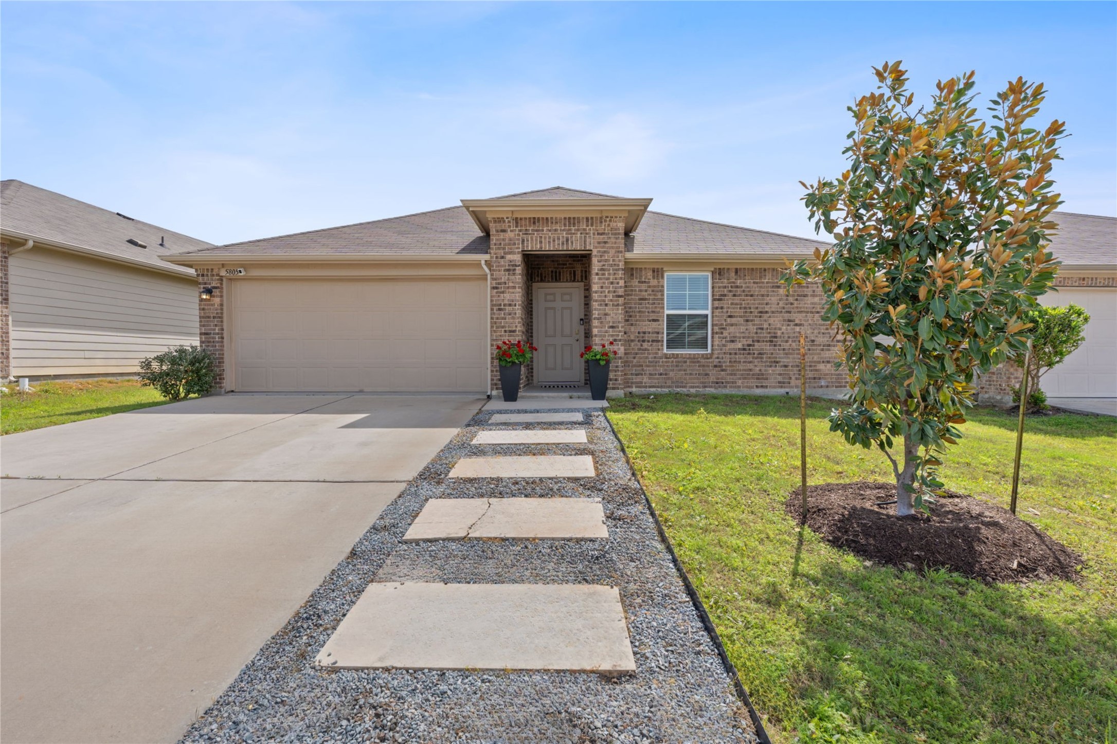 View of front of home featuring a garage, driveway, a front lawn, and roof with shingles