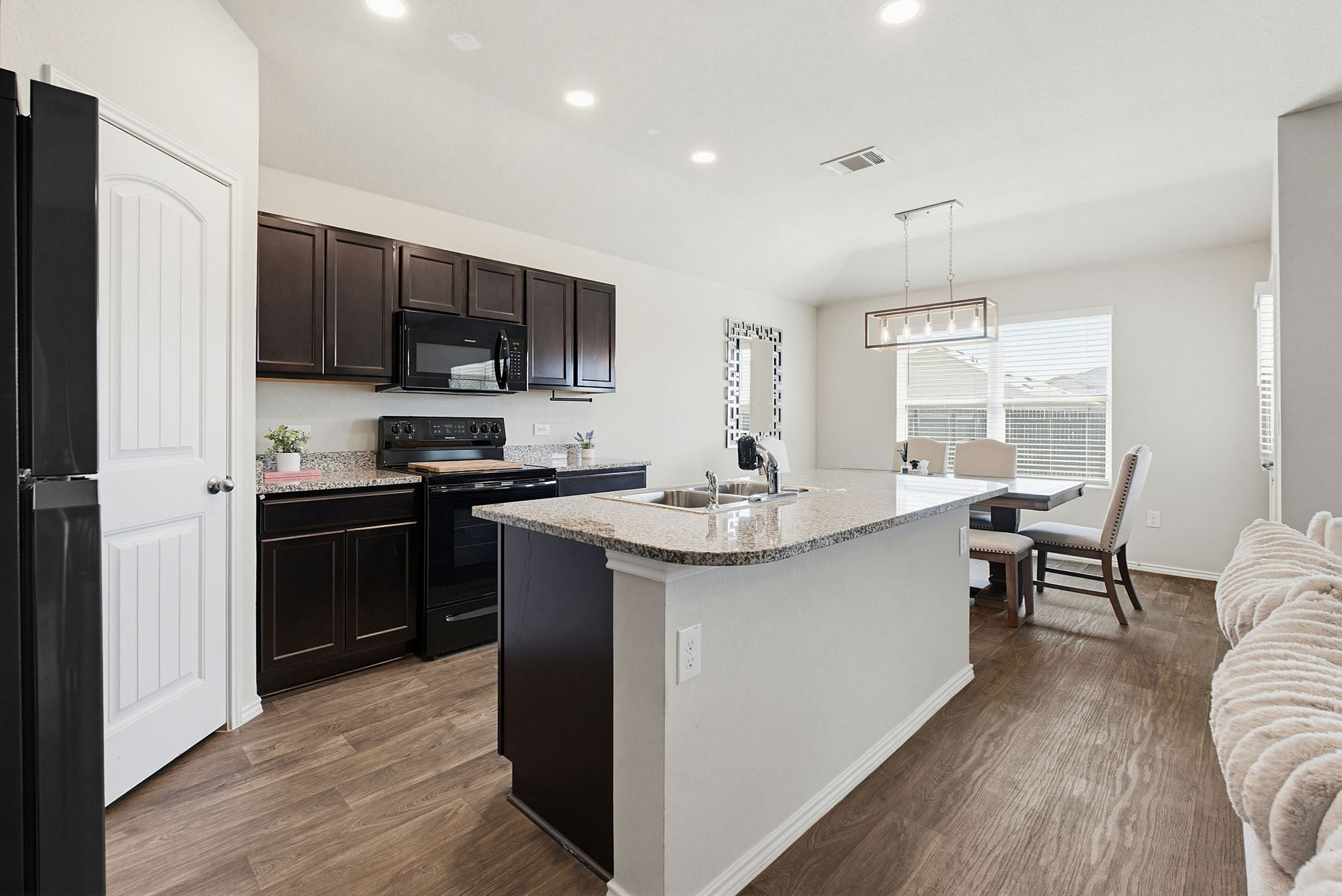5805 Brampton Lane Austin, TX 78724 - Photo 2 of 17 Kitchen featuring black appliances, dark wood-style floors, a kitchen island with sink, and hanging light fixtures
