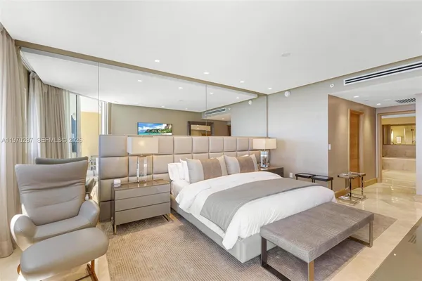 a spacious bedroom with a bed a couch and a flat screen tv