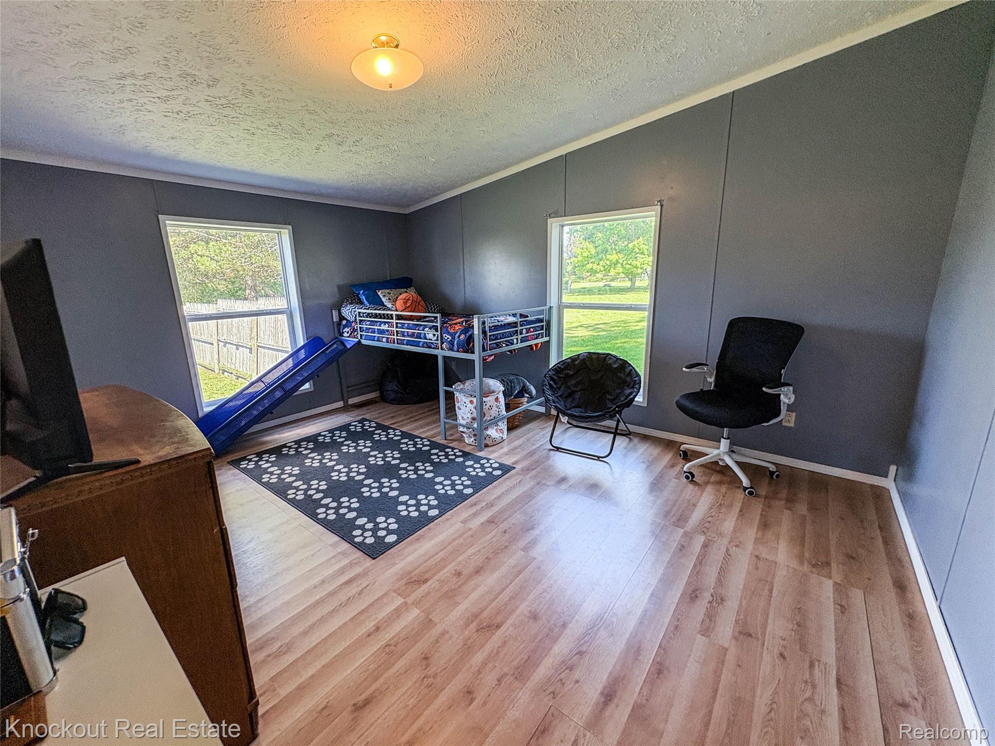 7760 Bell Road Birch Run, MI 48415 - Photo 44 of 68 Room featuring wood-finish flooring, two windows providing natural light, and gray wall paneling
