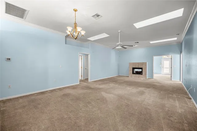 a view of an empty room with a chandelier fan