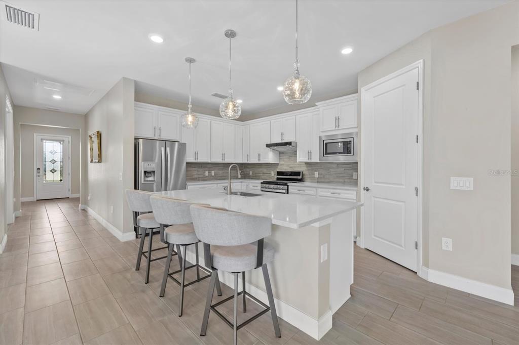 6835 Chester Trail Bradenton, FL 34202 - Photo 13 of 40 a kitchen with stainless steel appliances a refrigerator a stove a sink dishwasher and a dining table with wooden floor